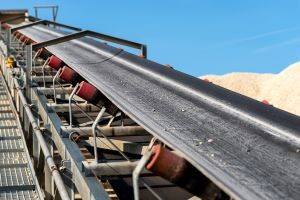 Close-up and upward angle of a conveyor belt with a clear blue sky in the background